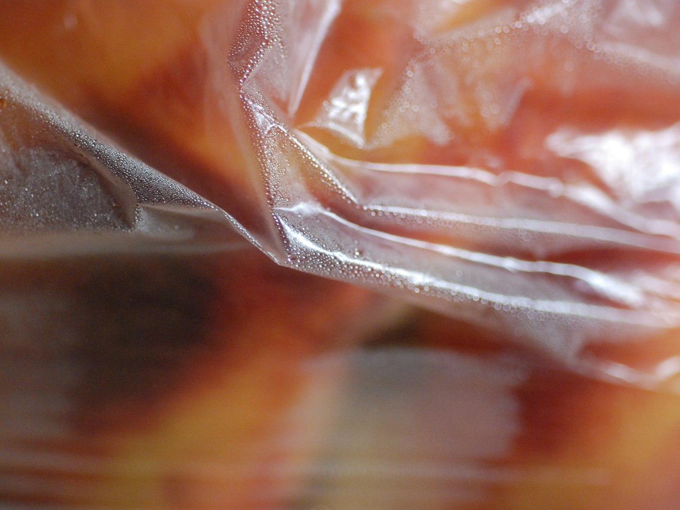 Charolas de carne y jamón termosellados avanzando en una línea industrial de empaque